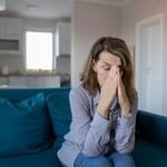 woman sitting on a blue couch having a chronic headache